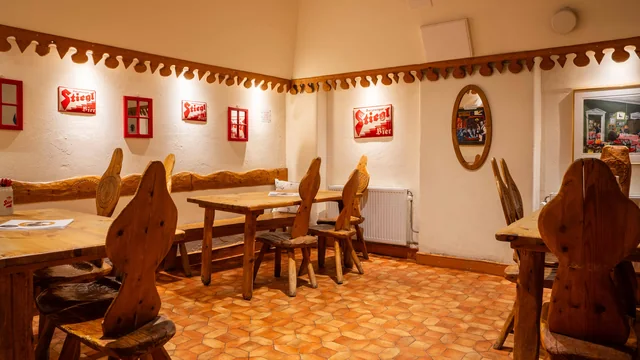Ett eget rum på Moldau med långbord, bänk, handskuren bård längs väggen och Stiegl-skyltar